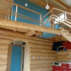 玄関ホールからアーチをくぐると吹き抜けのLDKが広がる ログと赤のキッチンと空色のLDK