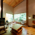 渓流の木々を眺めたり、ロッキングチェアに座り、読書や音楽鑑賞を楽しむ 薪ストーブのある天井の高いリビング