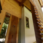 木製ルーバーと漆黒の丸太を抜けると木製の玄関ドアへ