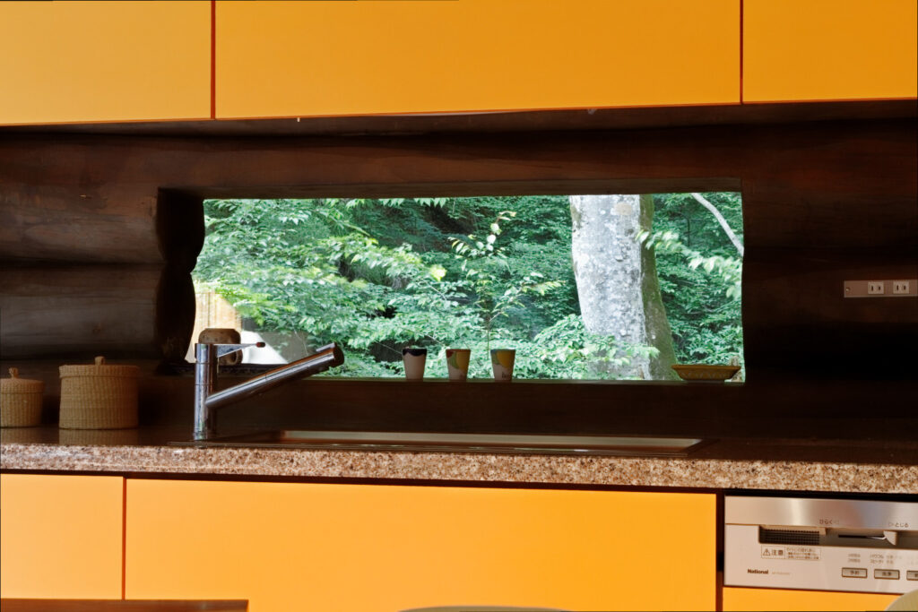 オレンジ色のキッチンと渓流の木々の緑